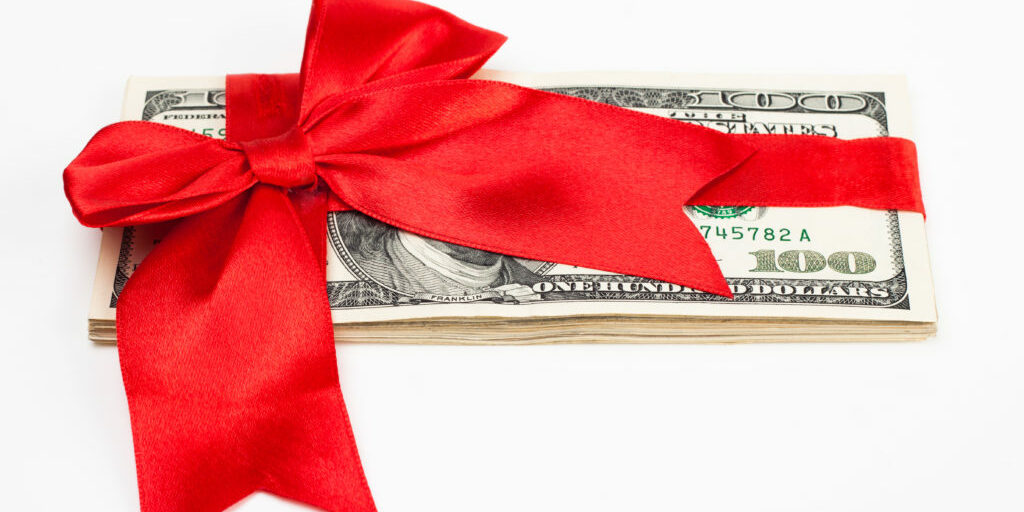 Several $100 bills wrapped with a red ribbon